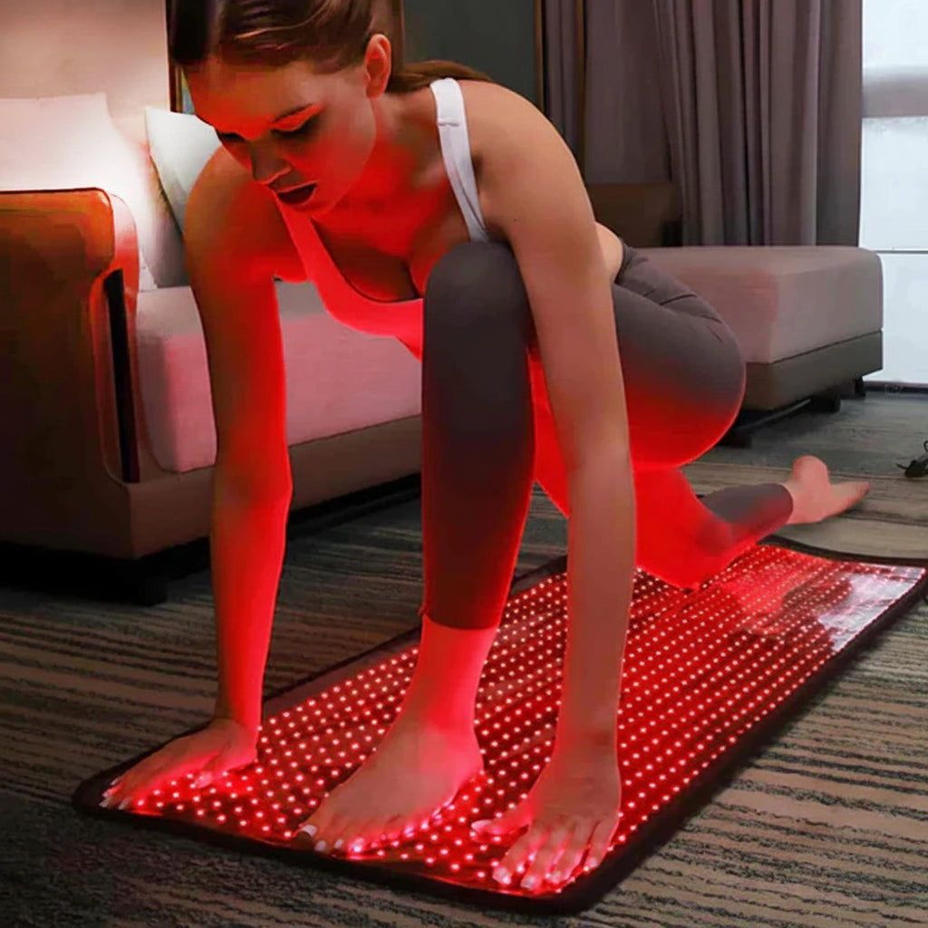 Woman using red light therapy mat for skin and muscle recovery at home